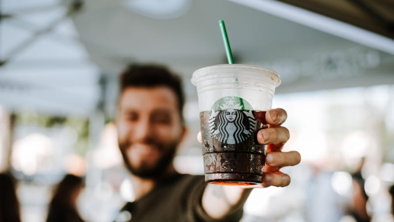 person holding a starbucks plastic cup