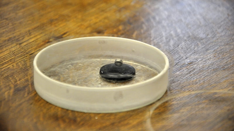 The special properties of a superconductor (black) cause a magnet (silver) to levitate. Bethany Hubbard/SCIENCE IN SOCIETY