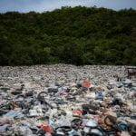 A landfill in front of trees, full of plastics -- including non-recyclable polyurethanes